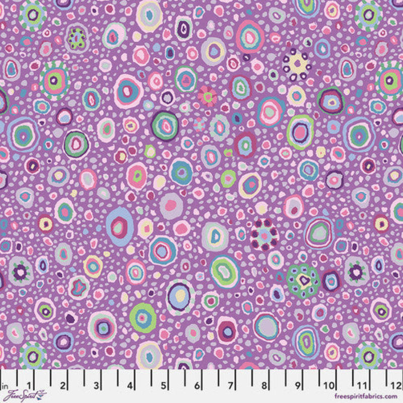 Lähikuva Kaffe Fassett Collectiven Roman Grass Lavender PWGP001.LAVEN -puuvillakankaasta, jossa on täpläkuviointi lilan ja muiden sävyjen vivahteilla. Sopii täydellisesti tilkkutöihin ja ompeluun.