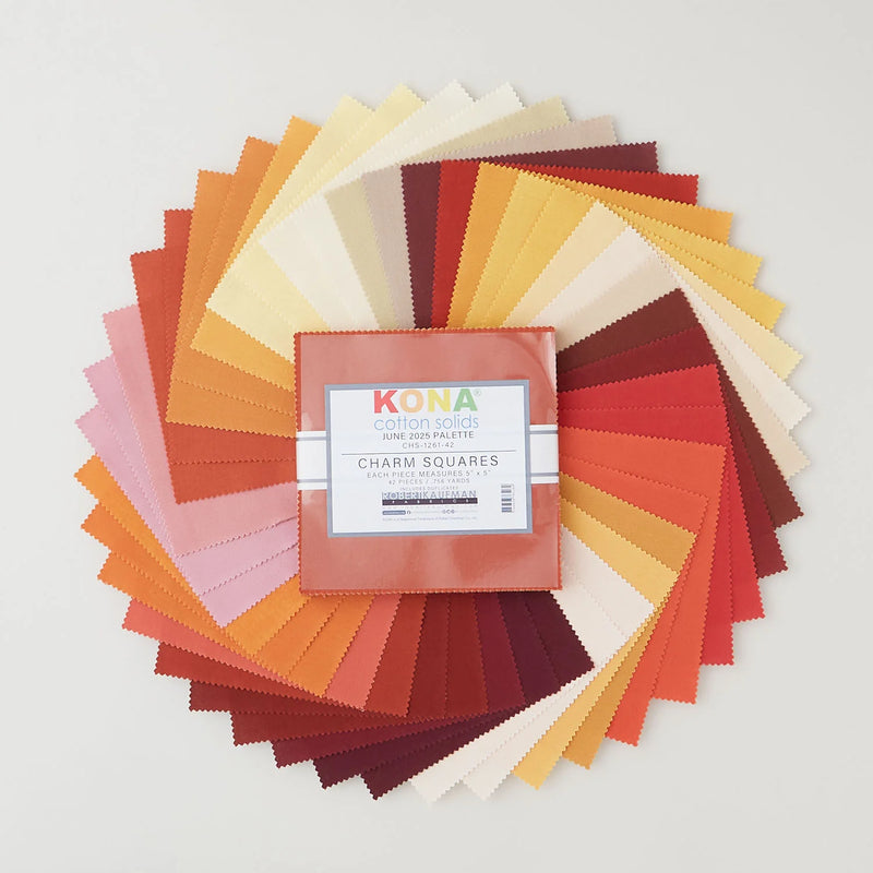 Kona Cotton Solids June Palette charm pack, 42 beigen, vaaleanpunaisen, oranssin, keltaisen ja ruskean sävyistä kangasneliötä viuhkana