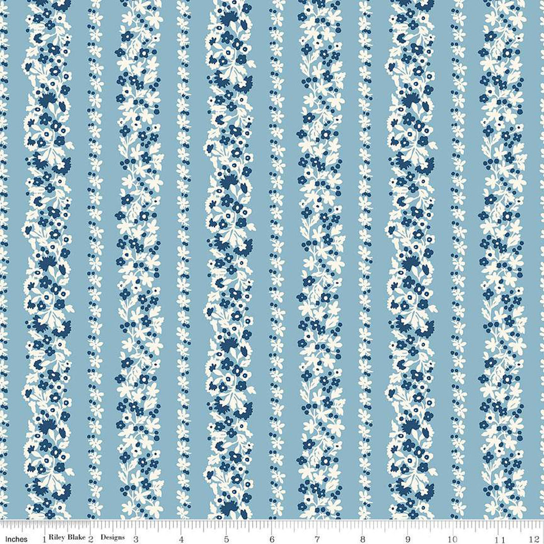 Vaaleansininen puuvillakangas, jossa on Liberty Londonin Denim Florals -kokoelman Topiary Stripe -kuosi. Kangasta koristavat pystysuorat kukkaköynnösraidat valkoisen ja sinisen sävyissä.