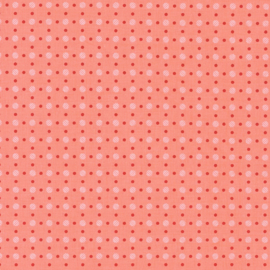Koraalinväinen puuvillakangas, jossa punaisia ja vaaleanpunaisia täplä-muotoisia pisteitä Lori Holtin Bee Basics -kokoelmasta, ihanteellinen tilkkutöihin ja ompeluprojekteihin.