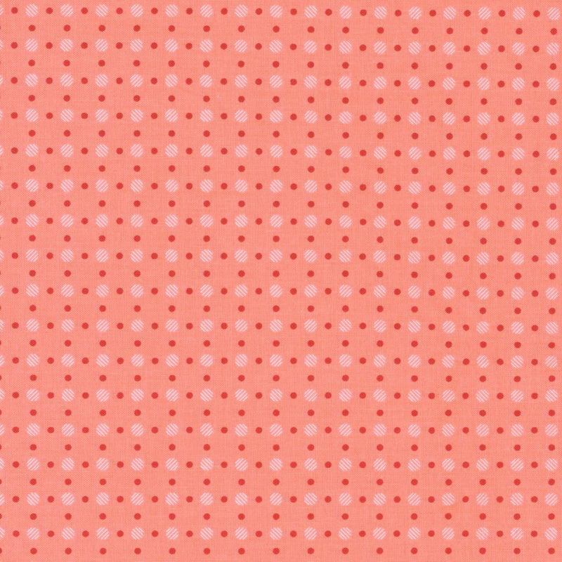 Koraalinväinen puuvillakangas, jossa punaisia ja vaaleanpunaisia täplä-muotoisia pisteitä Lori Holtin Bee Basics -kokoelmasta, ihanteellinen tilkkutöihin ja ompeluprojekteihin.