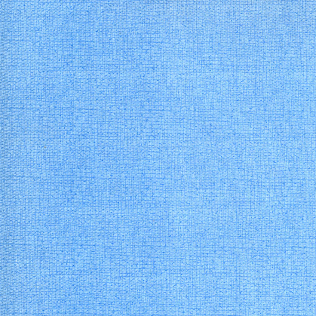 Robin Pickensin Thatched Mist -puuvillakangas, osa Cottage Bleu -kokoelmaa, tilkkutöihin ja käsitöihin.
Läheltä kuvattu Thatched-kuviointi: sinisen sävyt ja maalaisromanttinen tekstuuri.