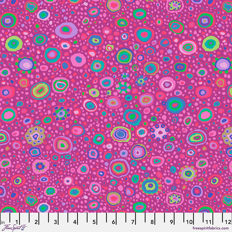 Lähikuva Kaffe Fassett Collectiven Roman Grass Violet PWGP001.VIOLET -puuvillakankaasta, jossa on täpläkuviointi lilan, vaaleanpunaisen ja muiden sävyjen vivahteilla. Sopii täydellisesti tilkkutöihin ja ompeluun.