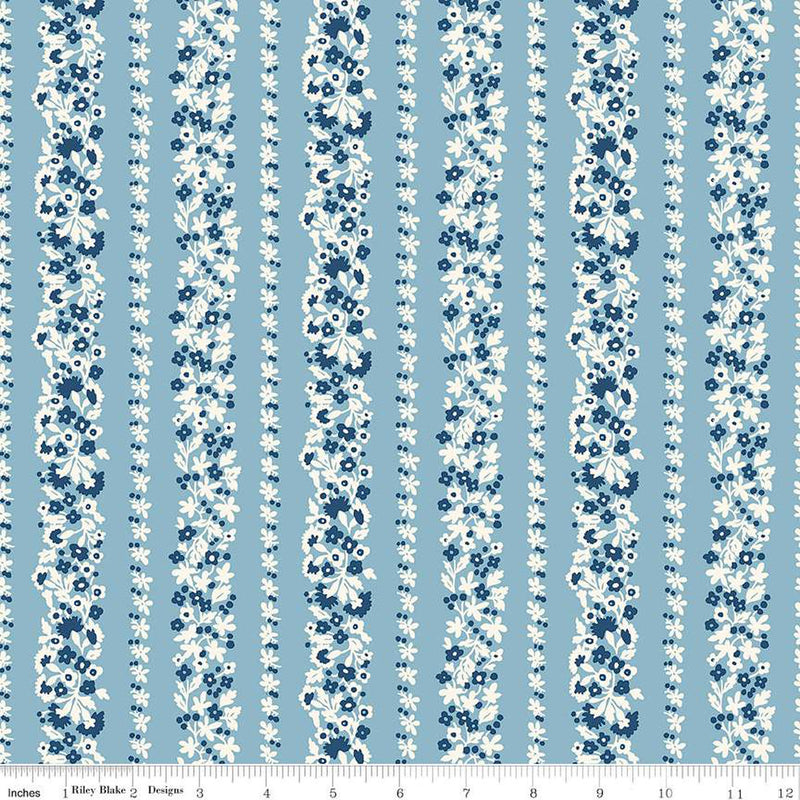 Vaaleansininen puuvillakangas, jossa on Liberty Londonin Denim Florals -kokoelman Topiary Stripe -kuosi. Kangasta koristavat pystysuorat kukkaköynnösraidat valkoisen ja sinisen sävyissä.