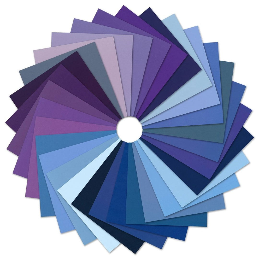 Kona Cotton Solids Tanzanite -charm pack viuhkaksi levitettynä: vaaleansinisen, laivastonsinisen, siniharmaan, violetin, ametistin ja luumun sävyjä