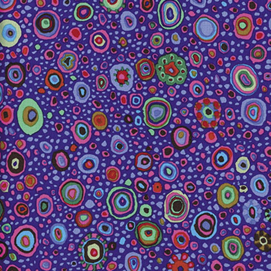 Lähikuva Kaffe Fassett Collectiven Roman Grass Lavender PWGP001.PURPL -puuvillakankaasta, jossa on täpläkuviointi lilan ja muiden sävyjen vivahteilla. Sopii täydellisesti tilkkutöihin ja ompeluun.