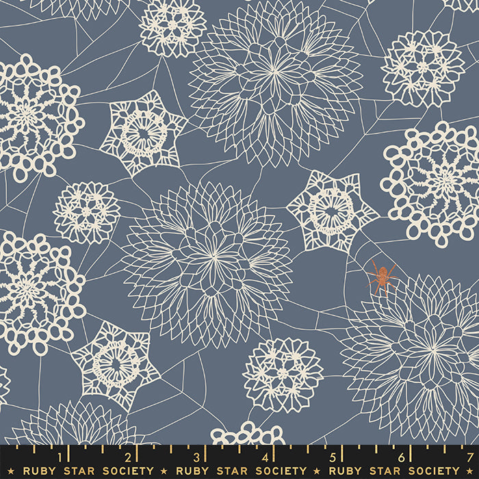 Harmaansinisellä pohjalla pitsimäisiä hämähäkinseittikuvioita ja oranssi hämähäkki, Ruby Star Society Spooky Darlings RS5076-16M Metallic Doily Spider Web Ghostly puuvillakangas.