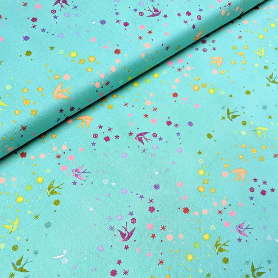 Tula Pink Fairy Dust Frolic - puuvillakangas, jossa on sateenkaaren värisiä pääskysiä ja tähtikuvioita turkoosilla pohjalla.